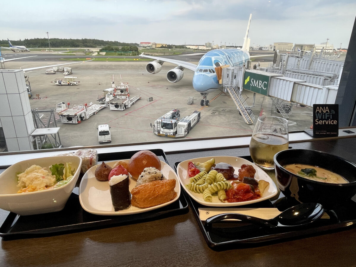 ANAラウンジで飛行機見ながら食事。おにぎりやサラダ飲み物が置いてあります。