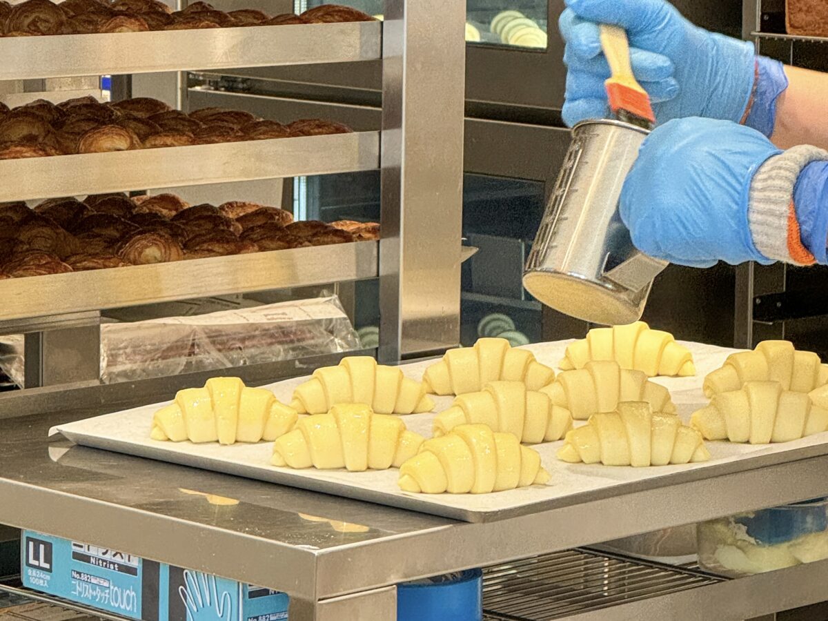 The process of applying egg yolk to croissant dough before baking