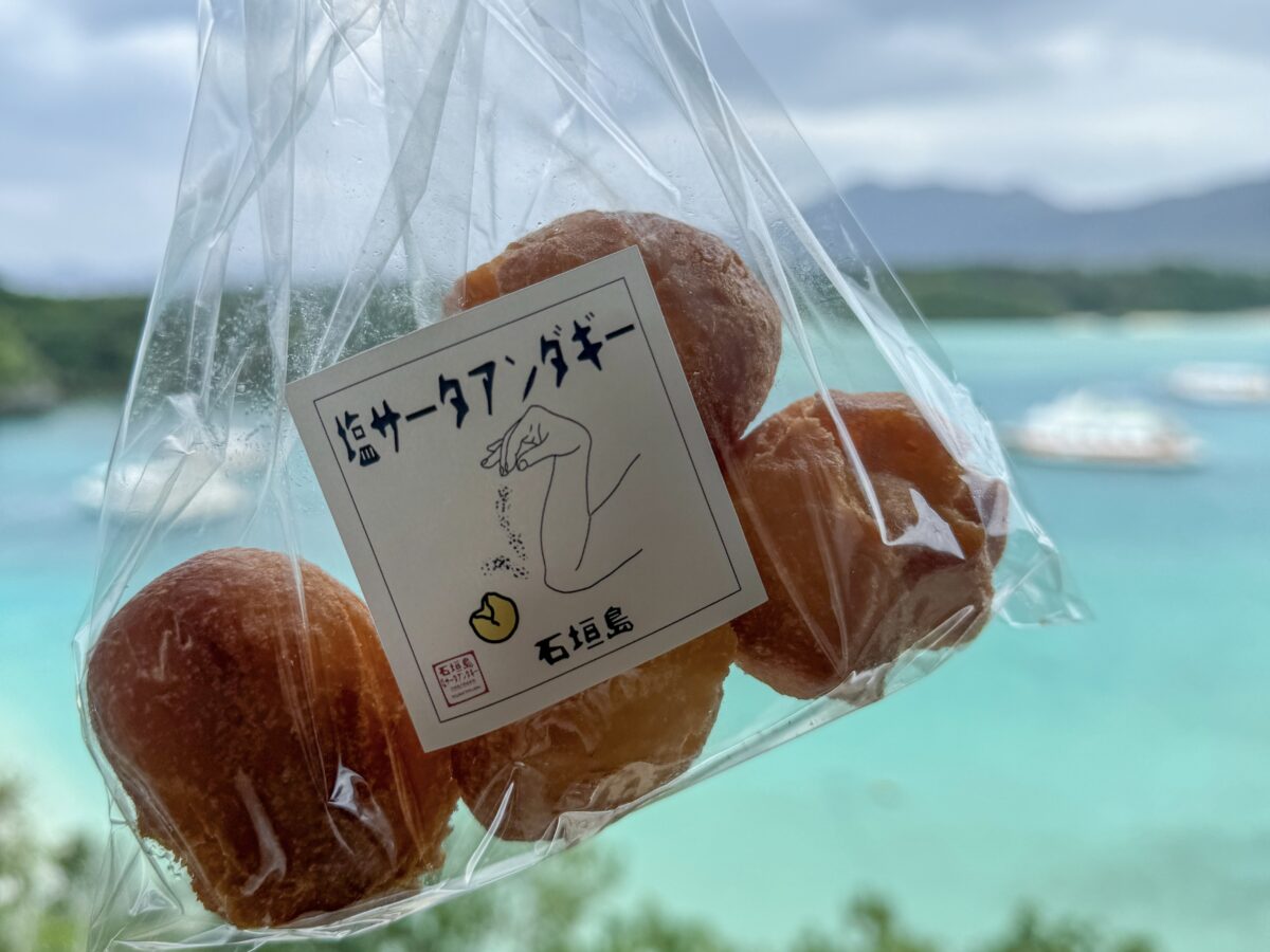 photo of a bag of salted sata andagi with Kabira Bay in the background